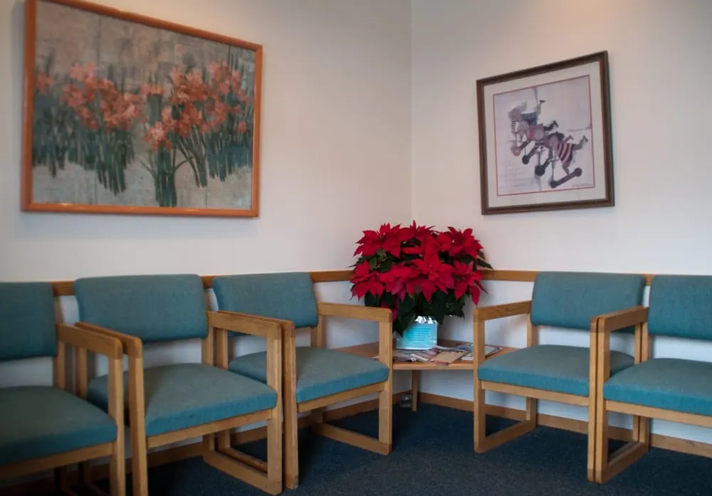 The waiting room at North Shore Dental, teal chairs beneath two framed prints.