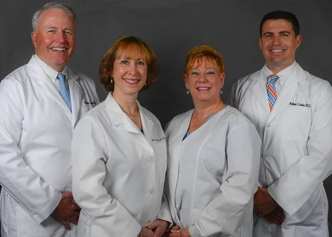 Dr. Michael E. Gordon, hygienists Jill Horwitz and Tamara Davis, and Dr. William E. Gordon, in white coats.